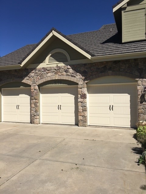 Almond carriage-house doors under stone arches
